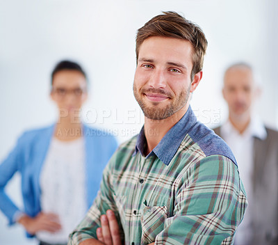 Buy stock photo Sincere looking young man with colleagues in the background