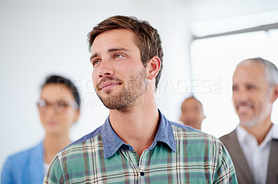Buy stock photo Young man looking away with coworkers in the background