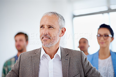Buy stock photo Positive mature man looking up with coworkers in the background
