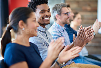 Buy stock photo Confident businessman smiling at the camera while applauding along with coworkers
