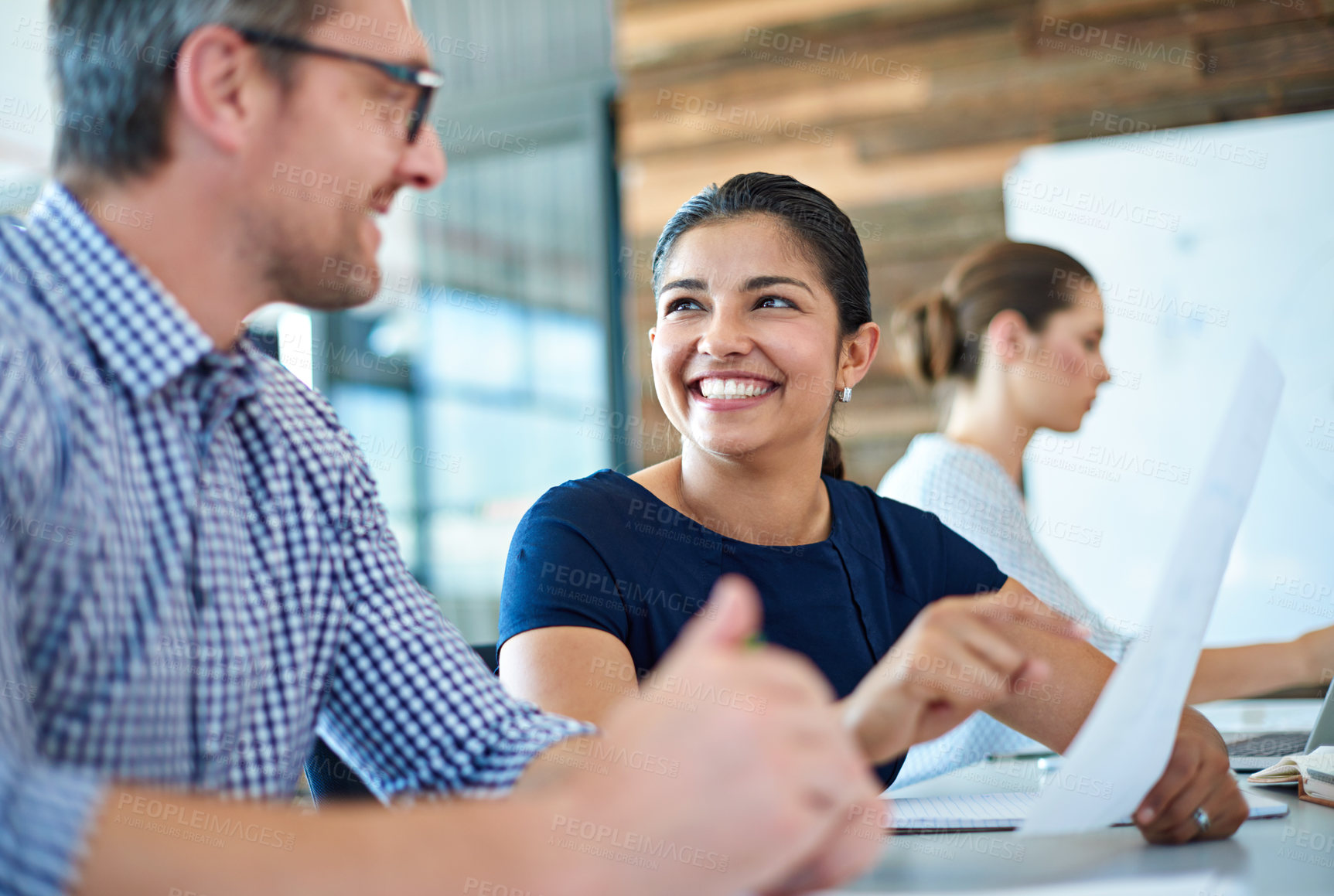 Buy stock photo Beautiful professional woman looking positively at a male coworker in a bright meeting room