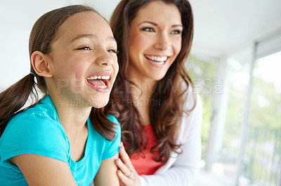Buy stock photo A cute daughter with pigtails laughing while looking off camera with her mother with copyspace