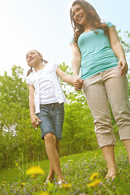 Buy stock photo A mother and daughter holding hands while walking in a meadow
