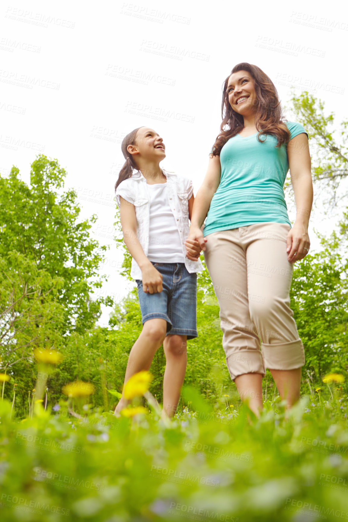 Buy stock photo A mother and daughter standing in a meadow laughing together while holding hands