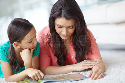 Buy stock photo A mother and daughter reading a magazine together