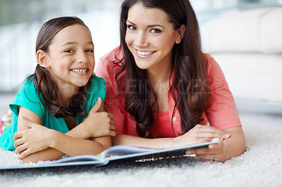 Buy stock photo A portrait of a mother and daughter lying on the floor with a magazine in front of them
