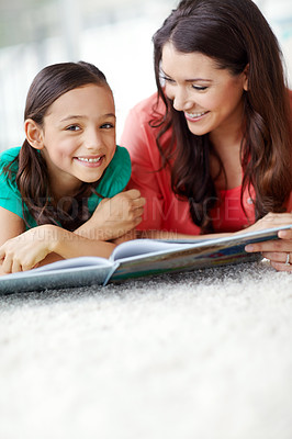 Buy stock photo A laughing mother and daughter lying on the floor with a magazine infront of them sharing a moment with copyspace