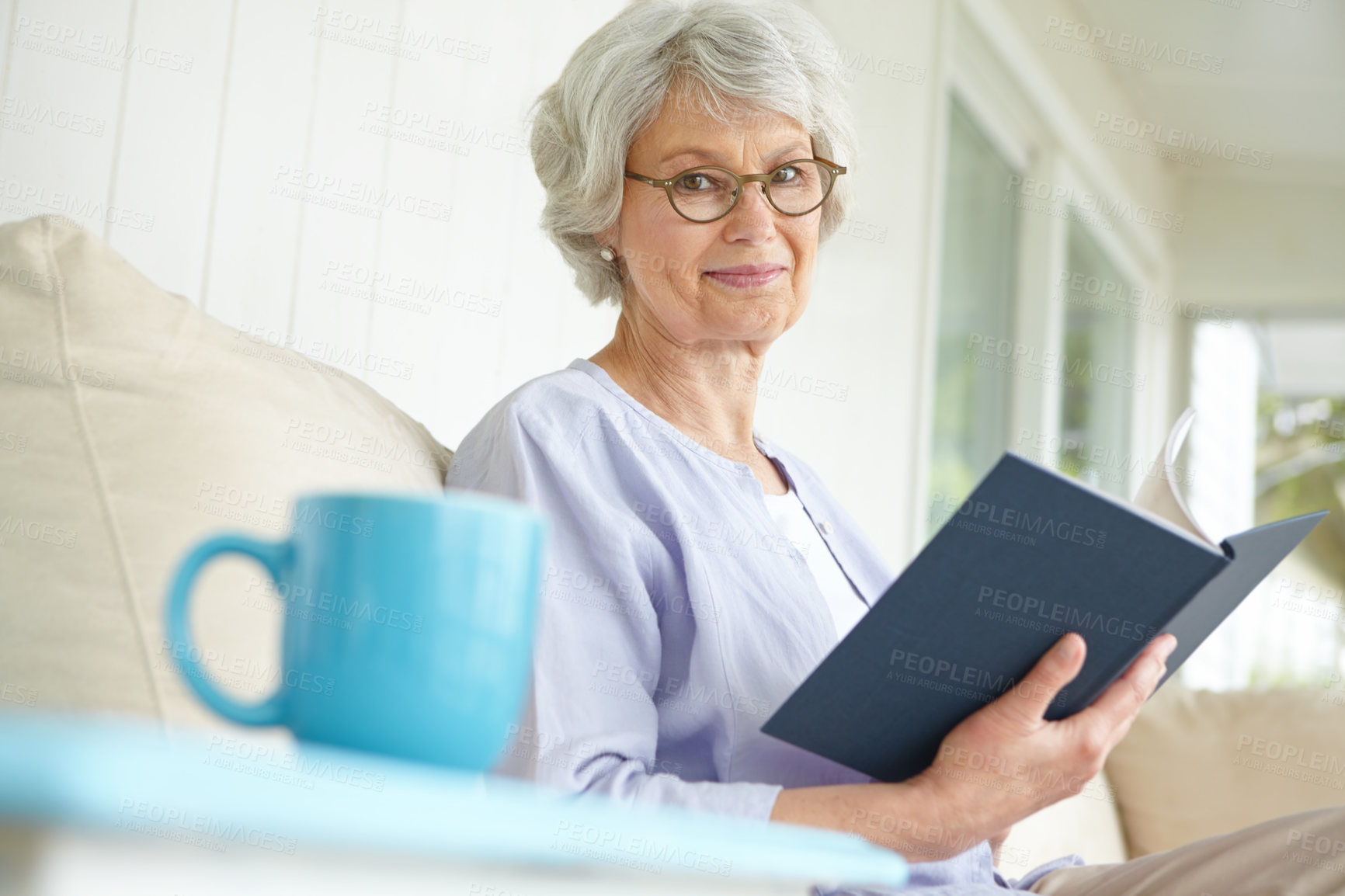 Buy stock photo Senior woman, portrait and reading with book for relax in retirement home on weekend for break. Elderly, female person and glasses as confident, happy and calm in living room on couch for knowledge