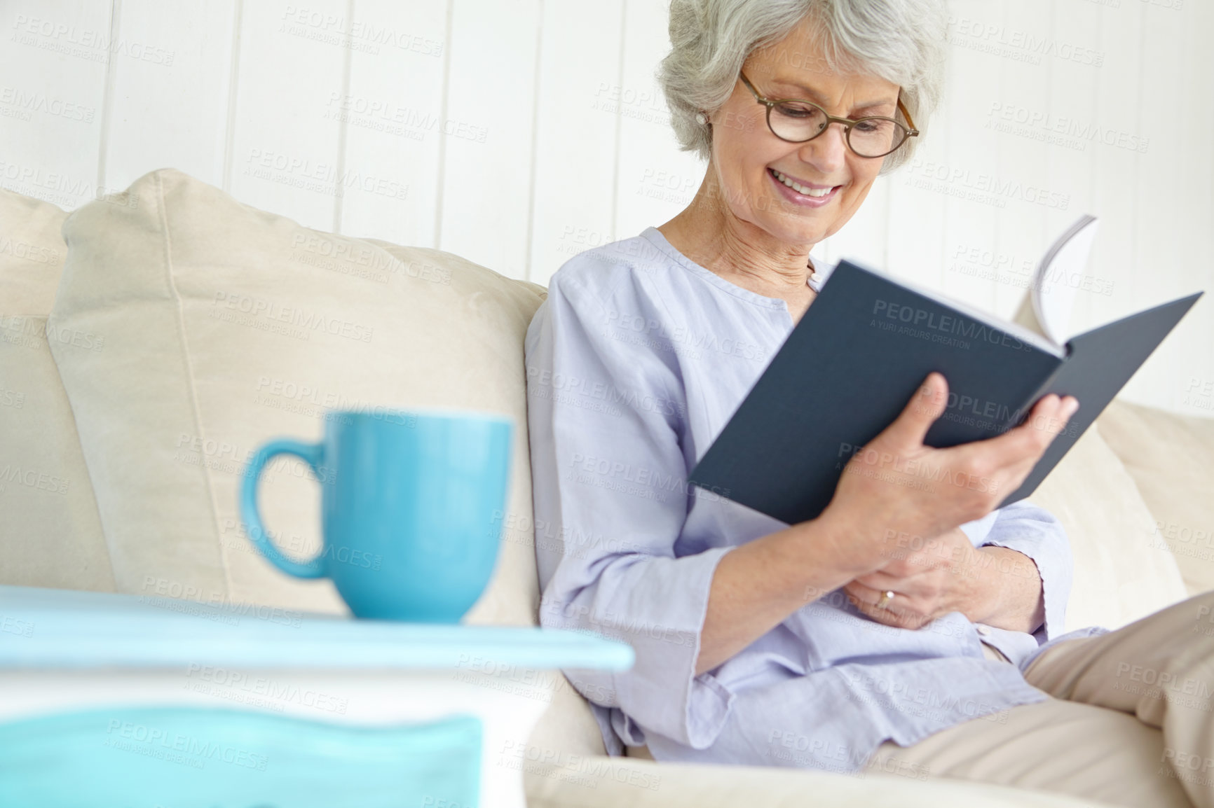 Buy stock photo Senior woman, happiness and reading book for education in retirement home on weekend on break. Elderly, female person and glasses as confident, cheerful and calm in living room on couch for knowledge