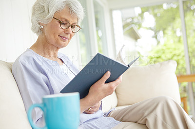 Buy stock photo Elderly woman, happiness and reading book for education in retirement home on weekend on break. Senior, female person and glasses as confident, cheerful and calm in living room on couch for knowledge