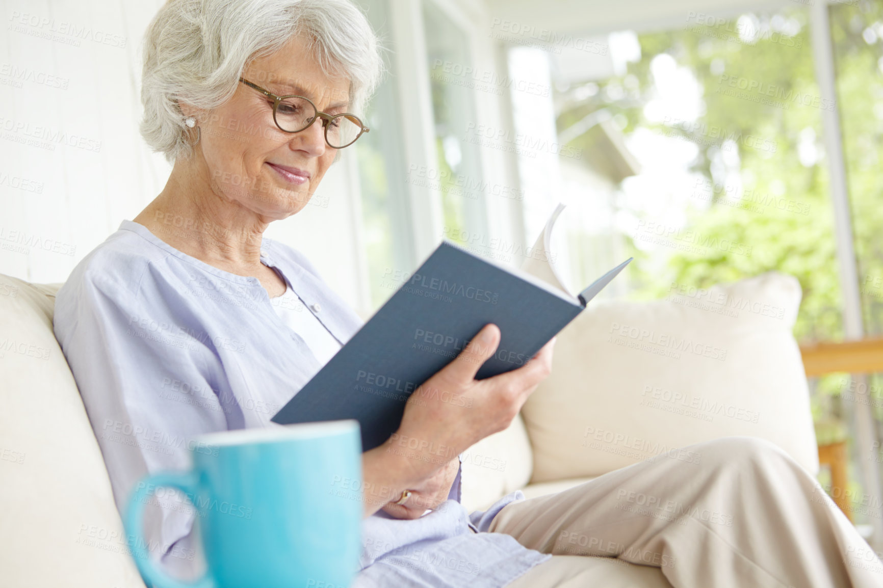 Buy stock photo Elderly woman, happiness and reading book for education in retirement home on weekend on break. Senior, female person and glasses as confident, cheerful and calm in living room on couch for knowledge