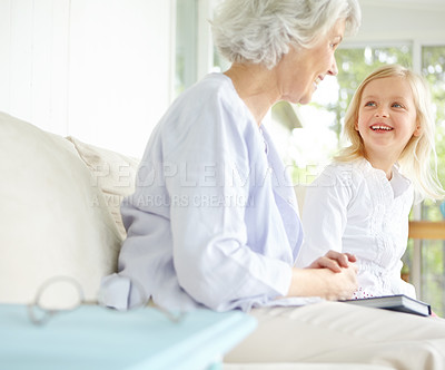 Buy stock photo Girl, senior grandma and book on sofa in home living room with woman, smile and story for retirement bonding. Happy, elderly person and weekend for rest, family and house lounge for memory on couch