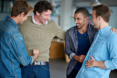 Buy stock photo Four male colleagues standing around having a bit of a joke together
