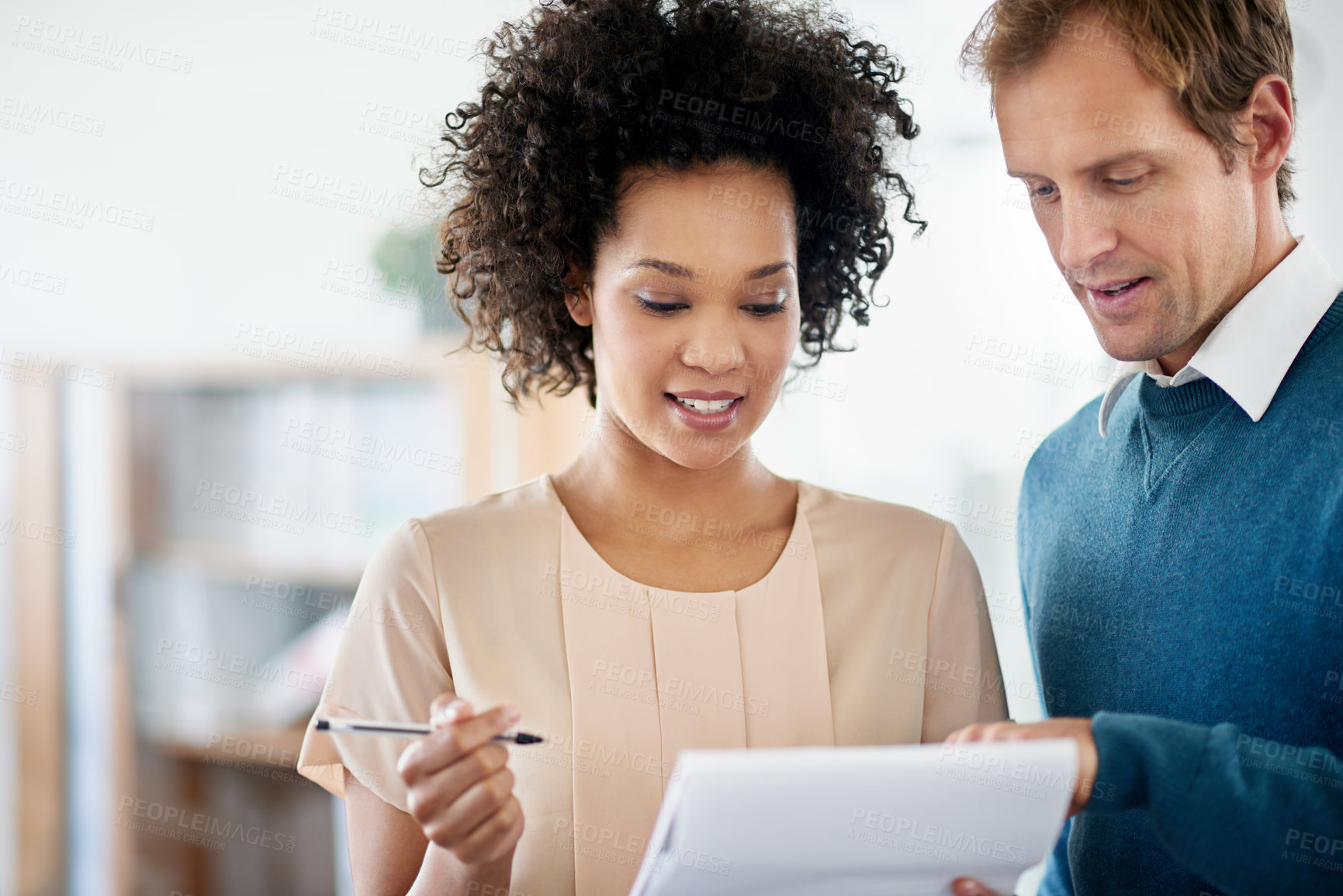 Buy stock photo Shot of two colleagues discussing ideas on a notepad