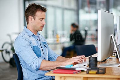 Buy stock photo Shot of a handsome young man working at his desk in an office