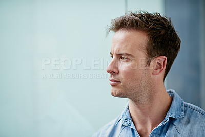 Buy stock photo Shot of a handsome young man looking thoughtful in a casual work environment 
