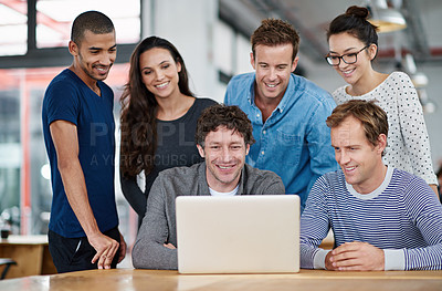 Buy stock photo Shot of a group of colleagues using a laptop together in a casual work environment 