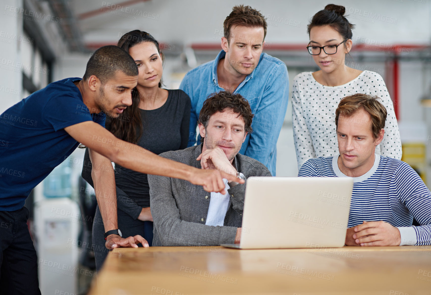 Buy stock photo Shot of a group of colleagues using a laptop together in a casual work environment 