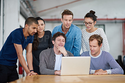 Buy stock photo Shot of a group of colleagues using a laptop together in a casual work environment 