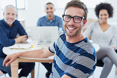 Buy stock photo Portrait of a young office worker sitting at a table with colleagues in the background