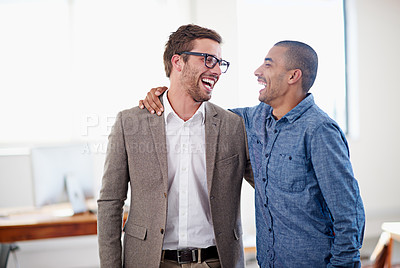 Buy stock photo Shot of two colleagues standing arm in arm in an office
