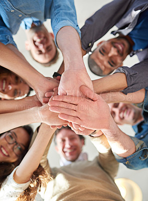 Buy stock photo Low angle shot of a group of co-workers stacking their hands on top of each other 