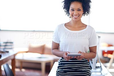 Buy stock photo Smiling african businesswoman holding a digital tablet with a bright office space in the background