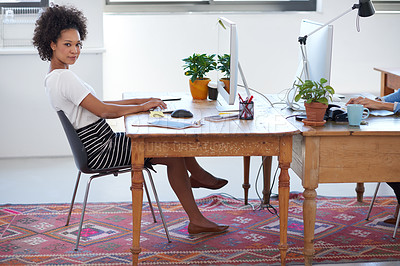 Buy stock photo Beautiful african woman sitting at her desk in an open creative office space