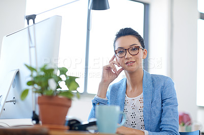 Buy stock photo Serious young woman looking at the camera in her bright office space