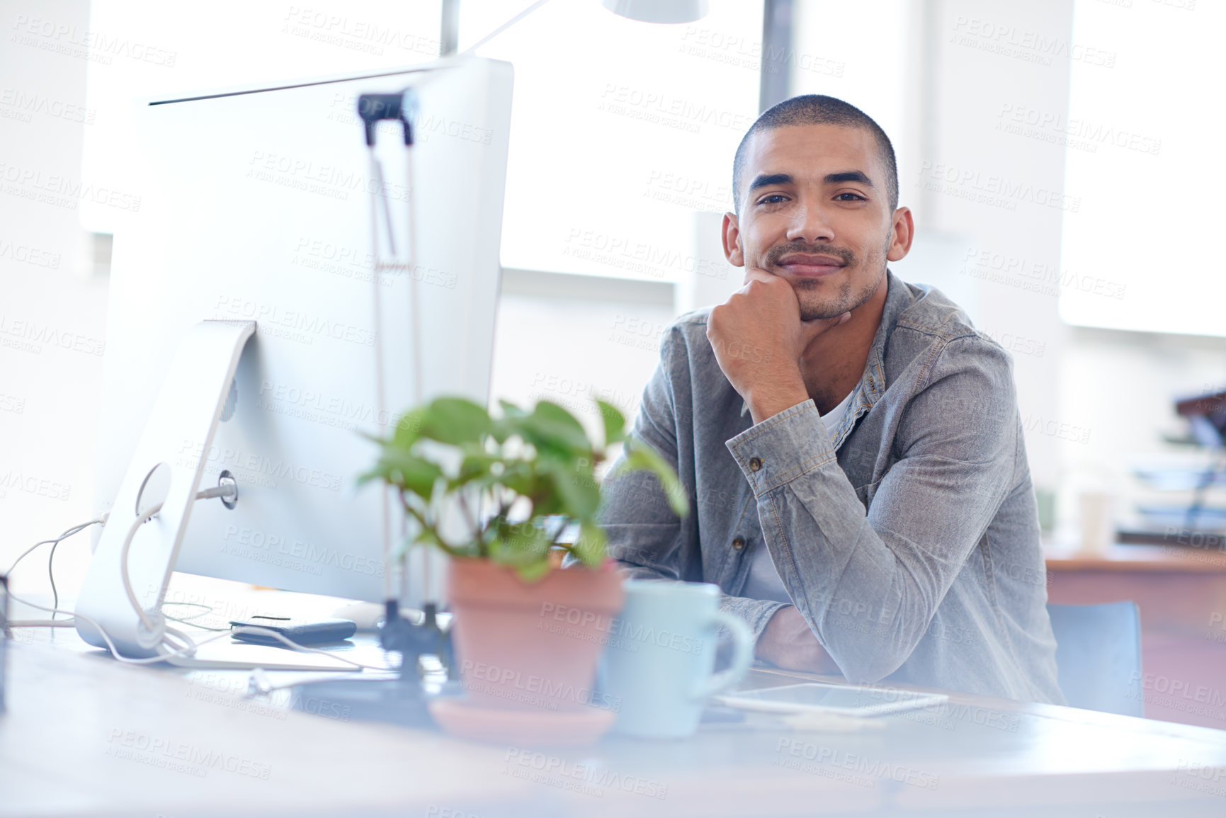 Buy stock photo Confident young man smiling at the camera while sitting at his desk