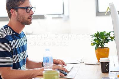 Buy stock photo Cropped shot of a handsome young man working on his pc in the office