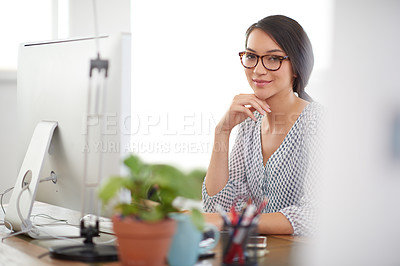 Buy stock photo Young woman sitting at her desk in a bright office space