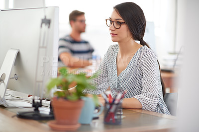 Buy stock photo Beautiful young woman working at her desk in a communal office space