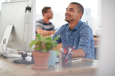 Buy stock photo Happy young man working at his desk in a communal work space