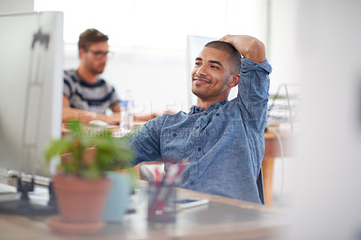 Buy stock photo Young creative professional smiling at his pc in a bright communal office space