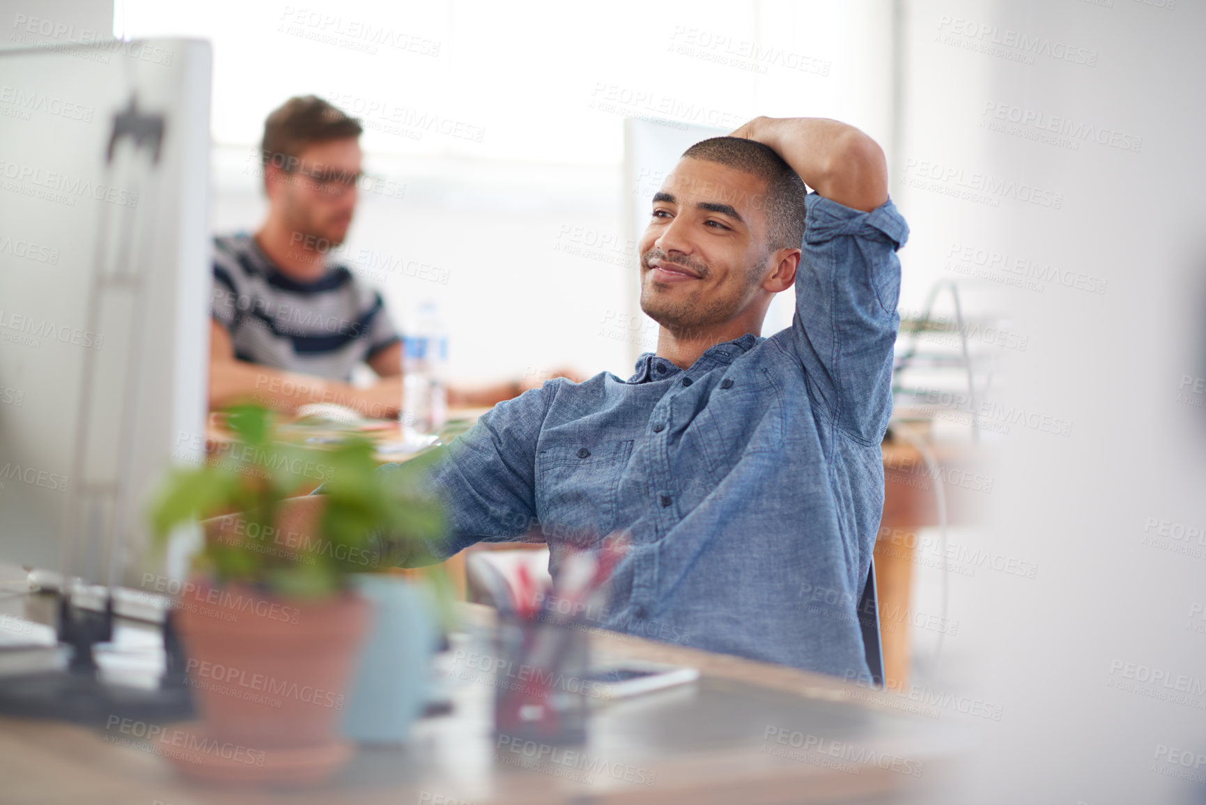 Buy stock photo Young creative professional smiling at his pc in a bright communal office space