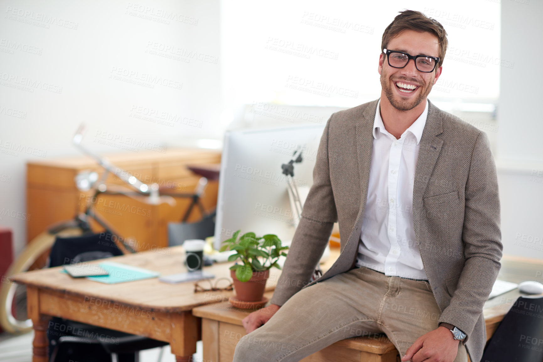 Buy stock photo Portrait of a smiling young designer sitting on his desk in an office