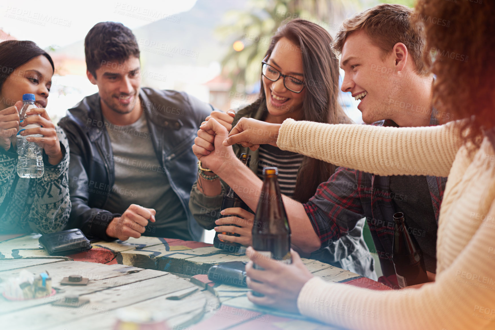 Buy stock photo Friends with beer, drinking and hands together in pub, restaurant outdoors and reunion on weekend. People, men and women with social gathering, celebration and alcohol with happiness or joy 