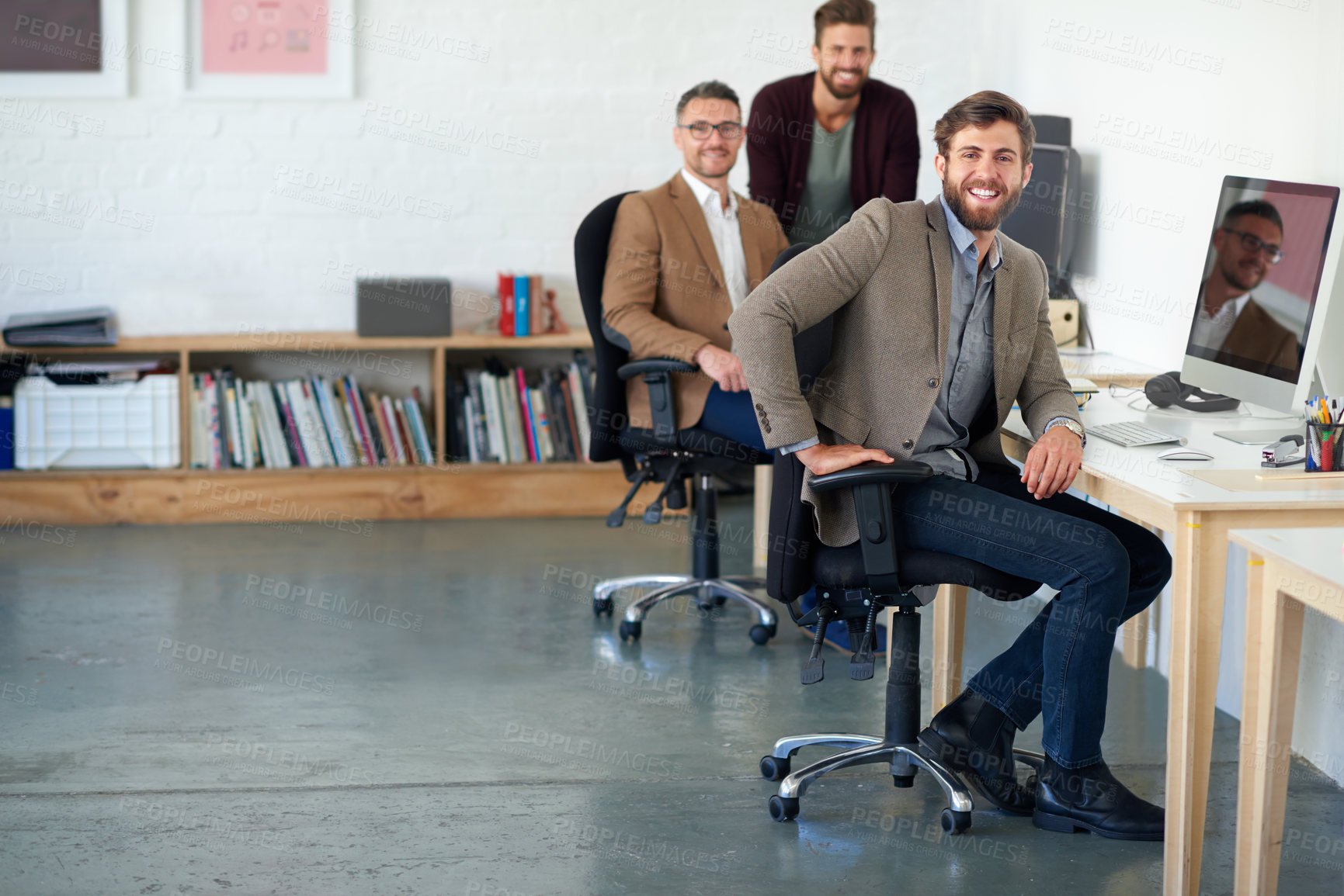 Buy stock photo Male colleagues smiling at the camera in their bright creative office space
