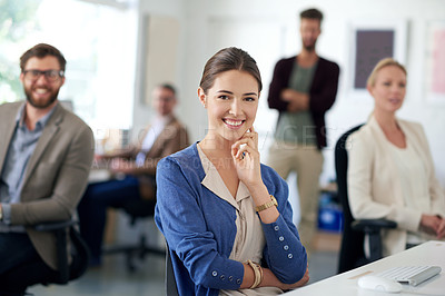 Buy stock photo Young businesswoman smiling at the camera with colleagues in the background
