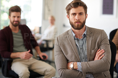 Buy stock photo Serious young businessman with his arms crossed and a colleague in the background
