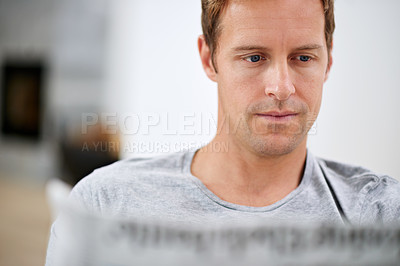 Buy stock photo Man, newspaper and reading in home to relax, calm and comfortable on weekend in living room. Male person, print update and article in apartment, information and rest on couch in pyjamas for story