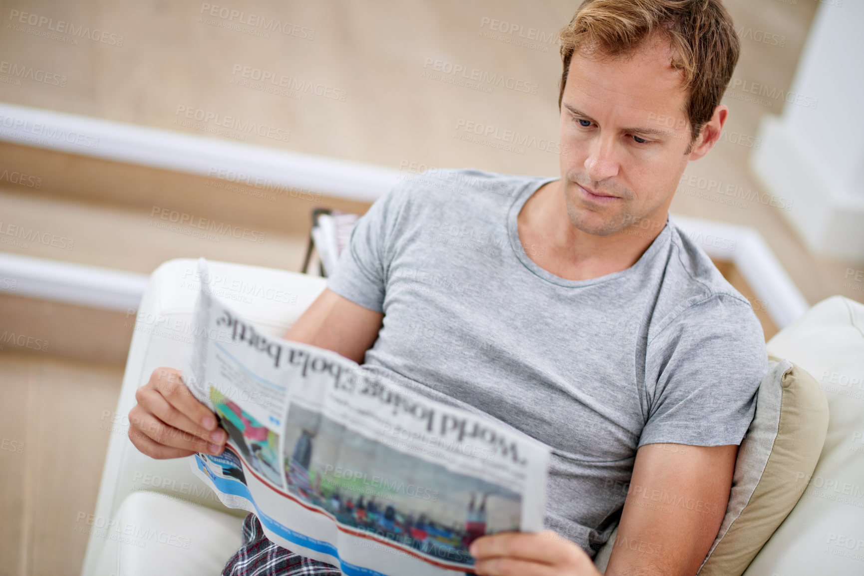 Buy stock photo Man, newspaper and relax on couch for peace, calm and comfortable on weekend in living room. Male person, reading and article in apartment, information and rest on sofa in pyjamas for story update