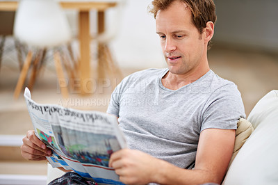 Buy stock photo Man, newspaper and relax in home for update, calm and comfortable on weekend in living room. Happy male person, reading and article in apartment, information and rest on couch in pyjamas for story