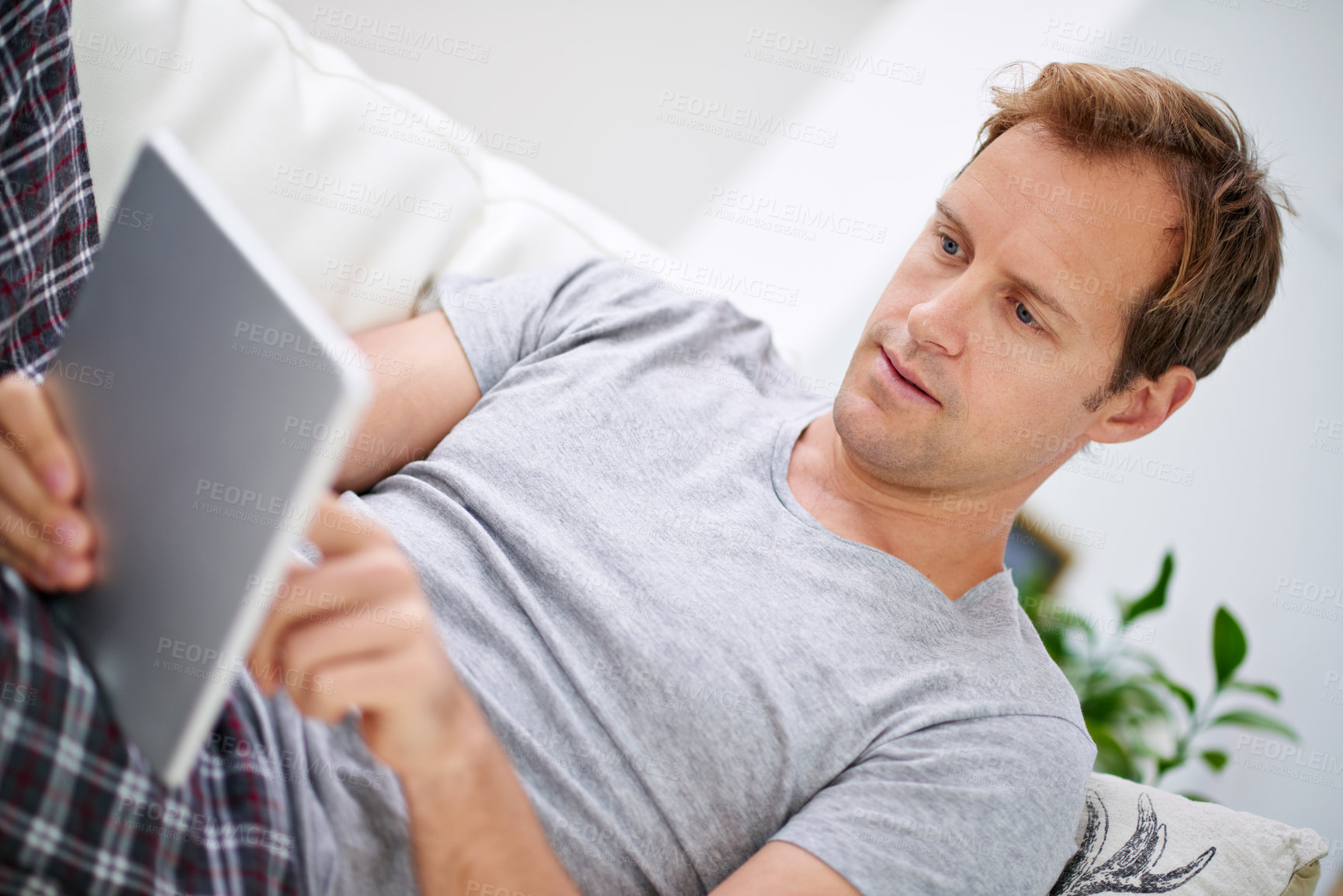 Buy stock photo Man, tablet and morning reading in home for web ebook or internet connection, connectivity or research. Male person, technology and online news on apartment sofa or article review, relax or lounge