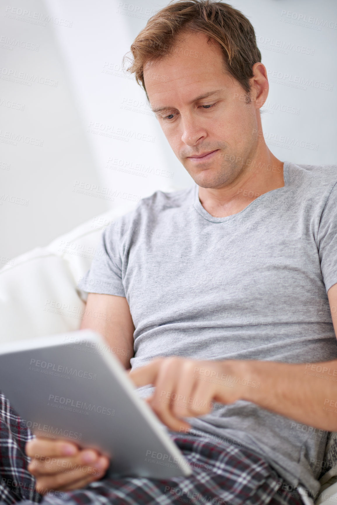 Buy stock photo Man, tablet and relax reading in home for online ebook or internet connection, connectivity or research. Male person, technology and web news on apartment sofa or article review, morning or lounge