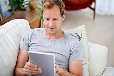Buy stock photo Man, tablet and reading online in living room for social media, movies and communication on sofa. Technology, research and pride at home for relax, internet and live streaming in apartment  