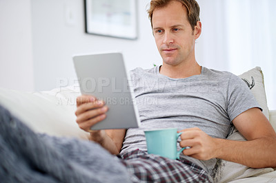 Buy stock photo Man, tablet and coffee break in living room for social media, networking and communication on vacation. Technology, reading and pride on couch for online company, work from home and ceo in apartment