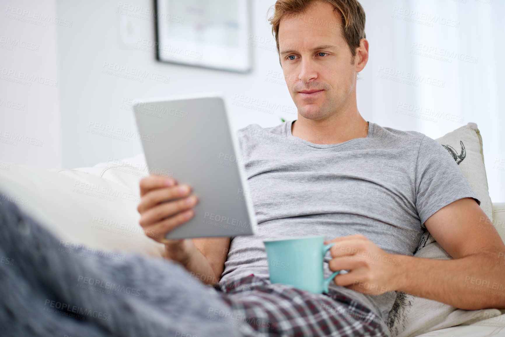 Buy stock photo Man, tablet and coffee break in living room for social media, networking and communication on vacation. Technology, reading and pride on couch for online company, work from home and ceo in apartment