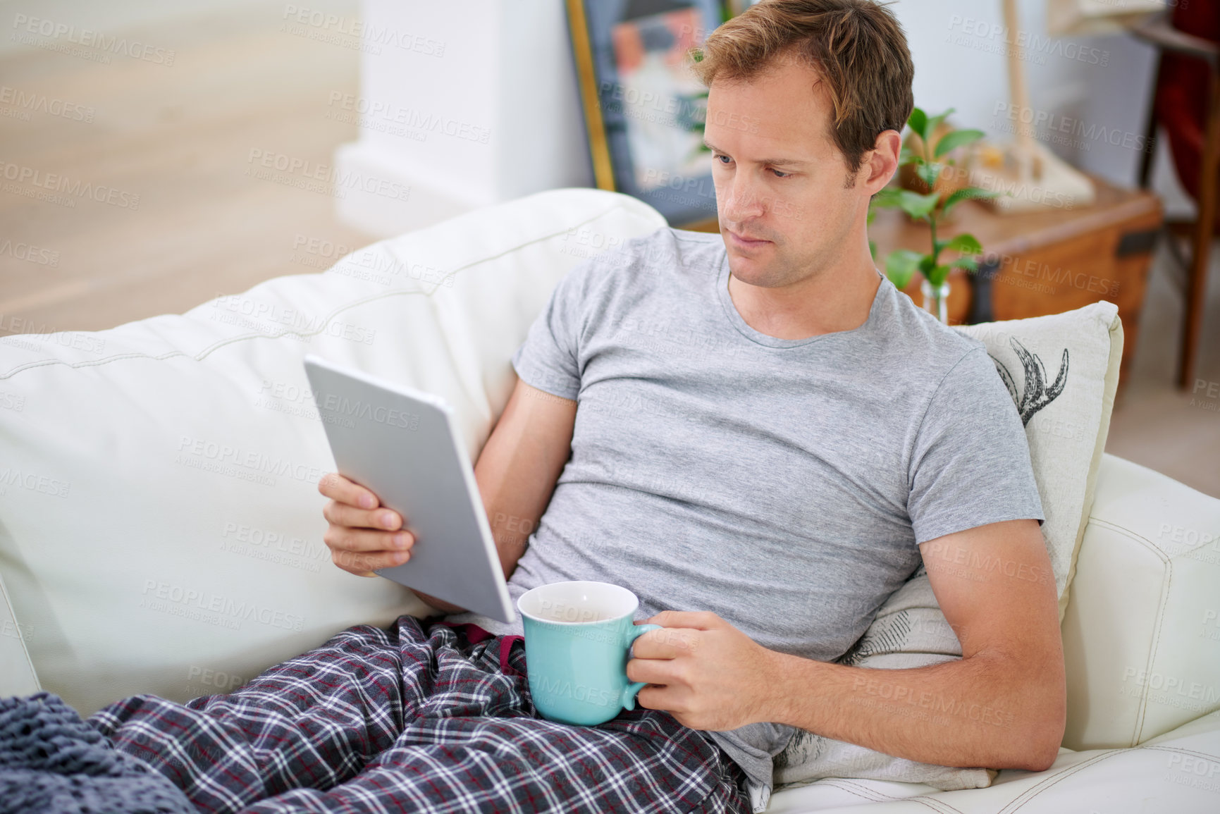 Buy stock photo Man, tablet and reading with coffee in living room for social media, networking and communication on vacation. Technology, relax and happy on couch for work from home, email and ceo of online company